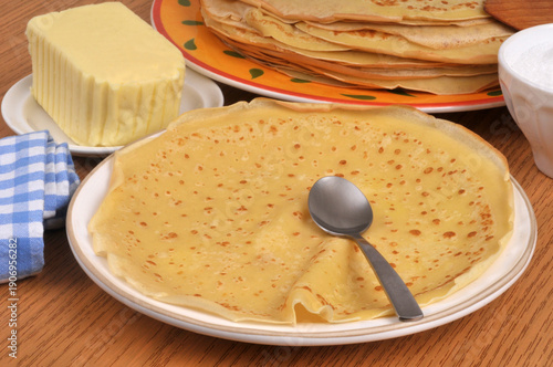 Crêpe dans une assiette avec une cuillère et du beurre au second plan