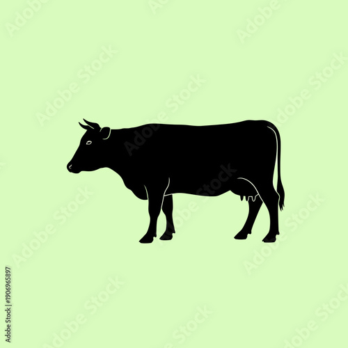 Cow silhouette standing on green background viewed from side