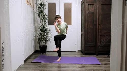 Caucasian boy stepping in place lifting his knee to elbow. Child doing sport exercise at home. Children workout. Strengthening the muscles. Strong sporty body. Active healthy lifestyle. 4k footage.