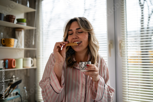 Cuadro en lienzo Woman enjoying morning coffee and cookie in kitchen