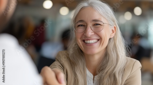 Confident mid aged business woman manager smiling and shaking hands with a colleague.