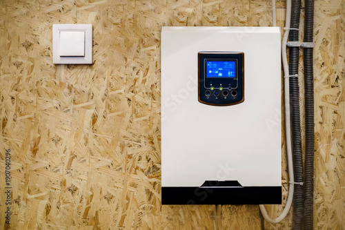 Solar Inverter mounted on Wall with Working Display Screen. Modern Aluminum Alloy Solar Hybrid Inverter and Switch 