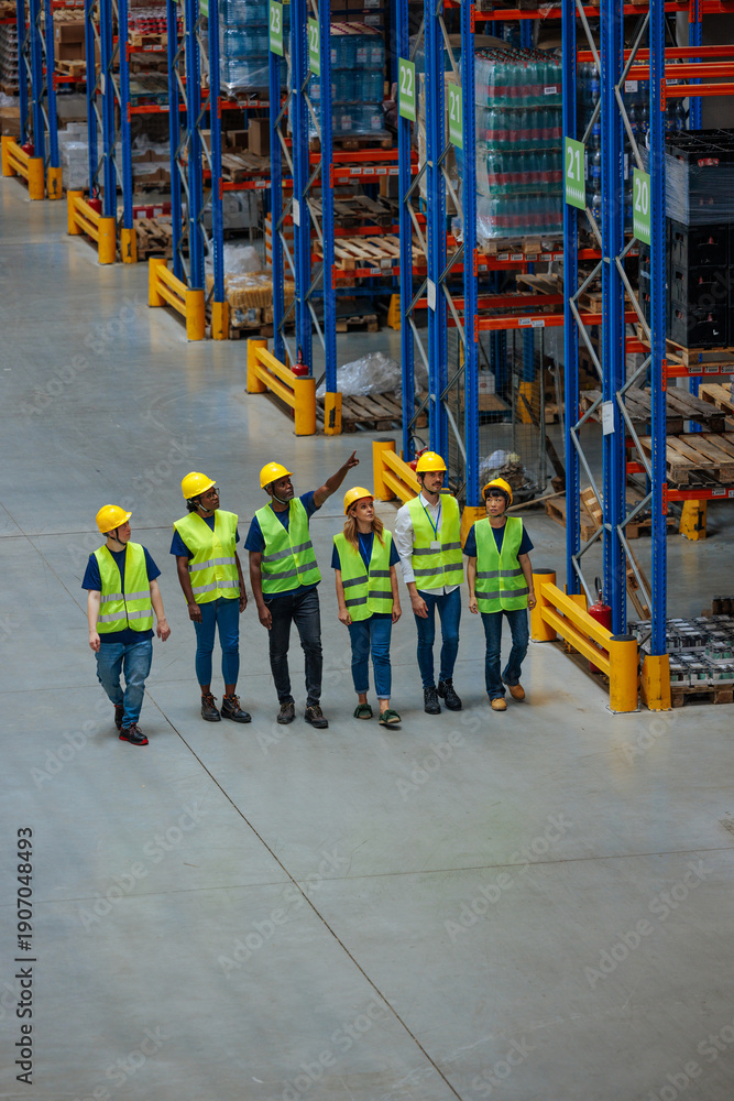 Fototapeta premium Group of warehouse workers in safety vests and helmets inspecting storage racks