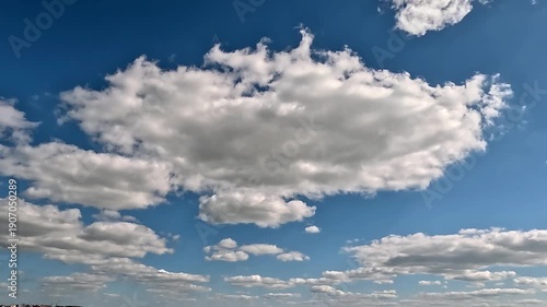Flowing forward fluffy clouds in the blue skies. 4K video (Ultra High Definition) of cloudscape. Sky and clouds Timelapse. Sun shines through the clouds on the blue sky background.