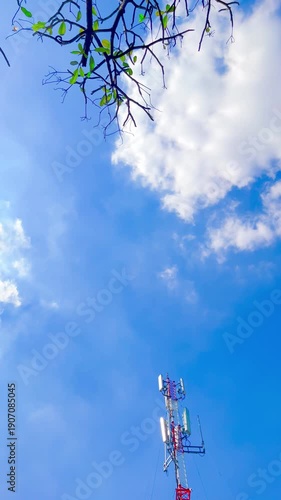 Rooftop Telecommunication Tower and Dish Aerials on Top of Building on Bright Blue Sky Background with Light and Green Leaves on Branches at Bangkok, Thailand. 05 JAN 2026, A.M./ Real Time Video