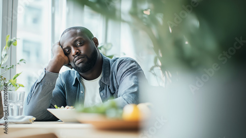 African American man looking bored eating healthy green salad, feeling tired, unhealthy diet, diet exhaustion