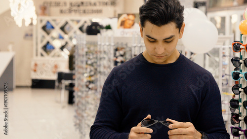 Cuadro en lienzo Man using smartphone while sitting in optics store shop