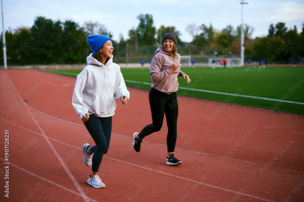 Obraz premium Female friends jogging together and talking on running track