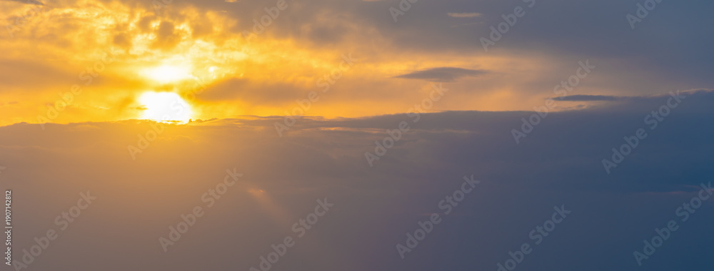 Fototapeta premium Cloudy Sunset Sky with Yellow Sun among Gray Clouds