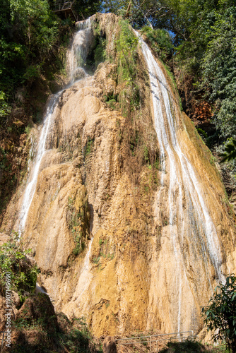 Tall Limestone Waterfall Flowing Down Cliff in Tropical Forest