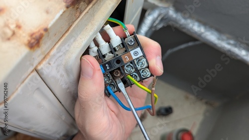 Wallpaper Mural Closeup hand tightens terminal screws on HVAC unit, wiring secured for reliable power, wiring repair supports safety, wiring maintenance fits electrician training, service promo Torontodigital.ca