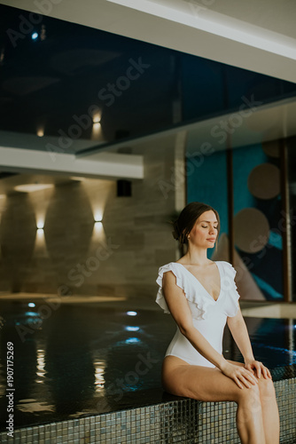 Woman sits by indoor pool i...