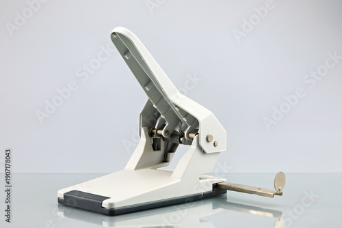 Foto A modern white and grey hole puncher stands open on a glossy surface against a bright background