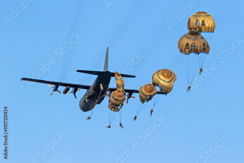 Military parachutist paratroopers parachute jumping out of an air force plane.