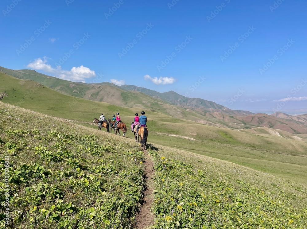 Obraz premium Horse riding in the breathtaking landscape of Song Kul Lake, Kyrgyzstan.