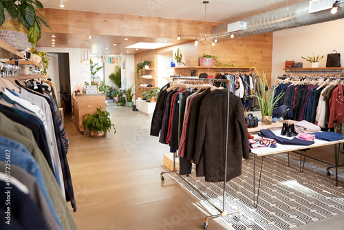 Tableau sur toile Bright modern clothing boutique with wooden floors, lush plants and neatly arran