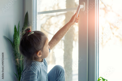 Little girl opens the window. Children safety at home. Prevention of falling accident