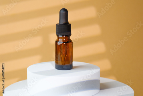 Amber glass serum dropper bottle on beige stone pedestal