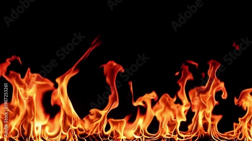 Intense fire flames burning brightly with glowing orange heat and flickering sparks against a solid dark black surface