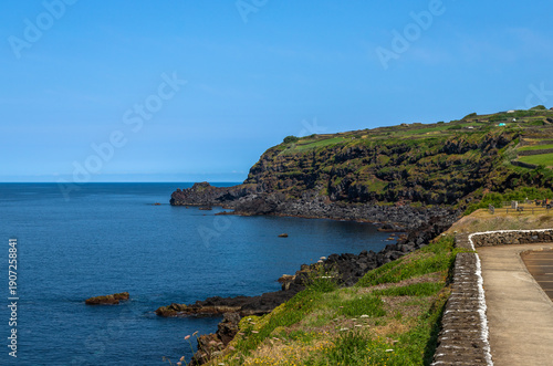 Volcanic natural swimming pools at Cinco Ribeiras on Terceira Island, Azores, Portugal. Black lava rocks, Atlantic Ocean waves and coastal bathing area under clear summer light