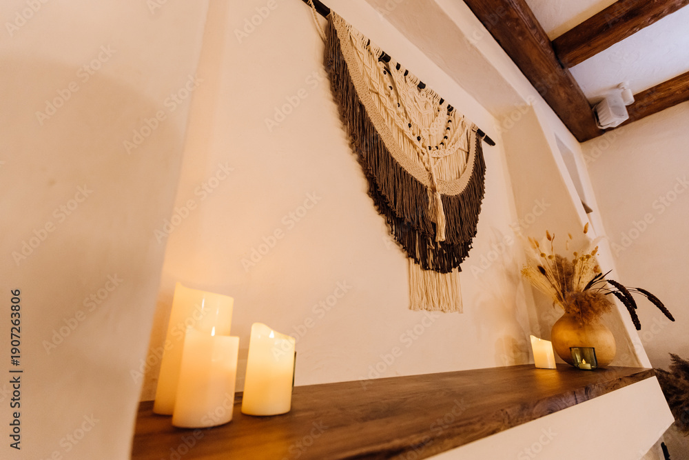 Obraz premium Boho macrame wall hanging with candles and dried flowers on rustic shelf