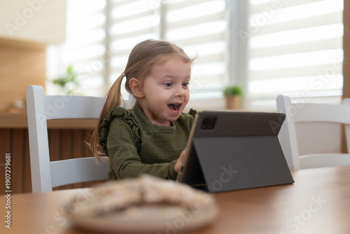 Schilderij op canvas Little girl feeling excitement watching digital tablet at home