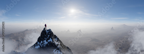 Bilde på lerret Climber Stands On Snowy Peak Overlooking Expansive Mountain Range At Sunrise