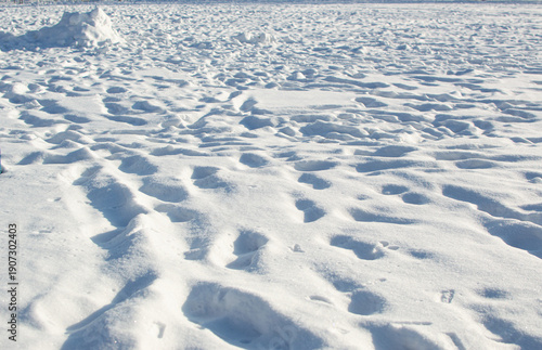 Deep tracks in white snow in winter, light and shadows on surface in sunlight