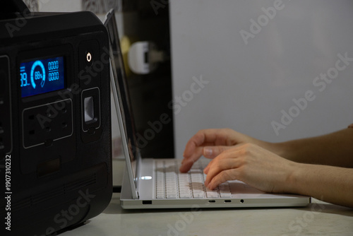 A girl works on a laptop connected to a portable charging station during a power outage in Ukraine. Working remotely without power, backup power, blackout, working from a battery