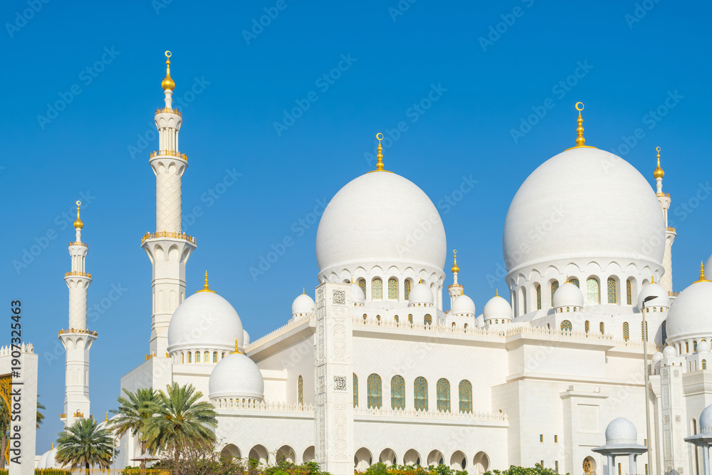 Obraz premium White domes and tall minarets of the Sheikh Zayed Grand Mosque against clear blue sky in Abu Dhabi, United Arab Emirates. Islamic architecture. Travel and tourism in UAE