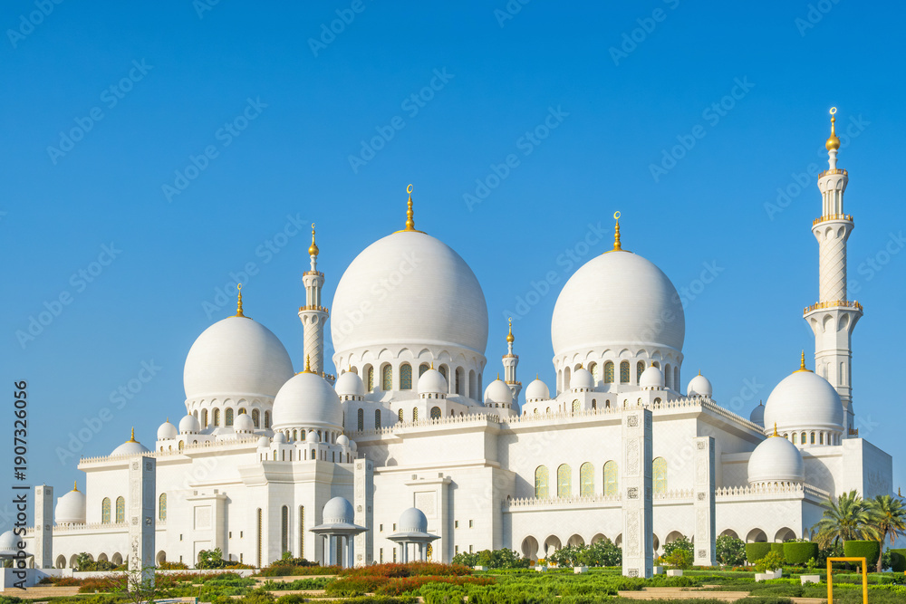 Fototapeta premium Sheikh Zayed Grand Mosque with multiple domes and minarets under clear blue sky in Abu Dhabi, United Arab Emirates. Islamic architectural heritage. Travel and tourism in UAE