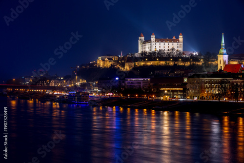 illuminated white Bratislava Castle above the Danube, against the background of a dark evening sky