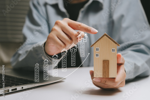 Real estate investment growth concept, hand holding wooden house model with upward chart, property value increase, housing market analysis, financial stability planning