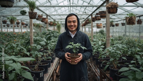 Man Holds Plant in Greenhouse Filled With Various Plants During Daytime