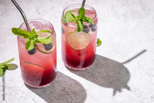 Fresh berry drinks with mint on a simple background