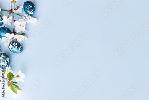 Easter flat lay. Stylish easter eggs and cherry flowers on blue background. Easter celebration, season greetings mockup. Spring modern floral banner