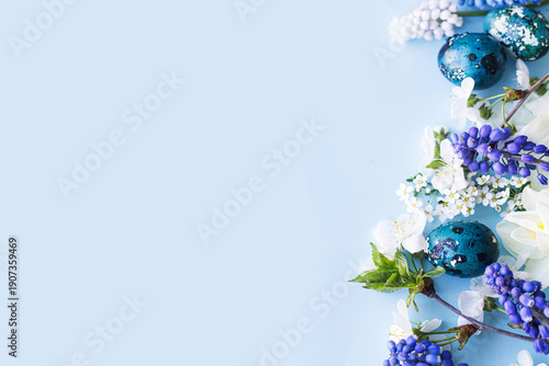 Easter flat lay. Stylish easter eggs, daffodils, and cherry flowers on blue background. Easter celebration, season greetings mockup. Spring modern floral banner