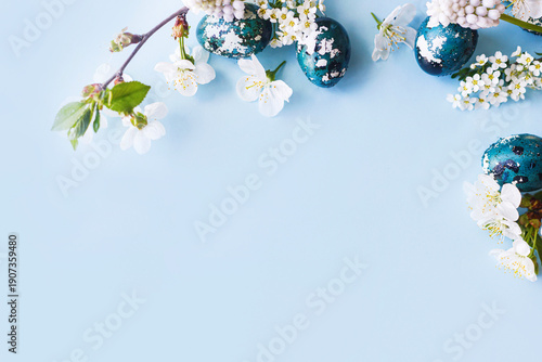 Easter flat lay. Stylish easter eggs and cherry flowers on blue background. Easter celebration, season greetings mockup. Spring modern floral banner