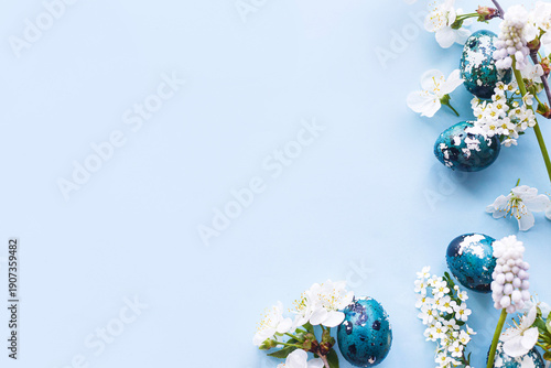 Easter flat lay. Stylish easter eggs and cherry flowers on blue background. Easter celebration, season greetings mockup. Spring modern floral banner