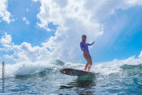 Принти на полотні Young Woman Standing On Longboard, Arms Raised, Sunlit Ocean Balance And Calm Ho