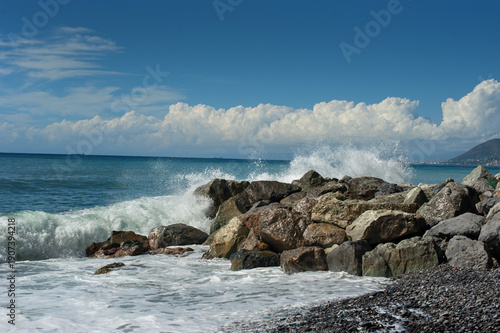 Sea waves crashing against a rocky shore on a sunny day
