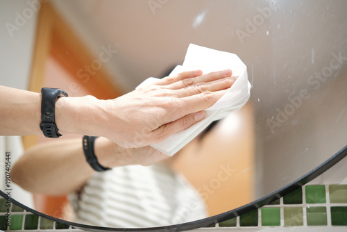 Billede på lærred Woman hand cleaning mirror with disposable glass cleaning wipes