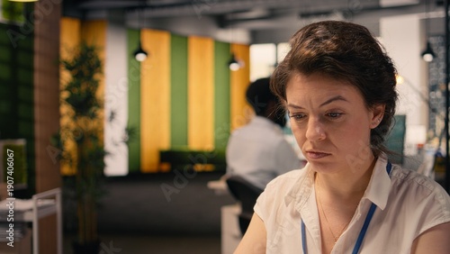 Fotografie Frowning businesswoman with confused and skeptical expression at desk, appearing uncertain and indecisive reviewing visual data on laptop