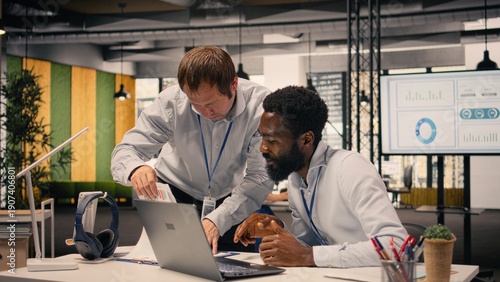 Photography Diverse corporate office scene with team collaboration around laptop and reports, research and development