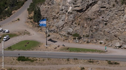 Argentine flag waving proudly over a scenic mountain road in San Martin de los Andes, Neuquen, Patagonia, representing national pride, federalism, and the spirit of the Argentine Republic.