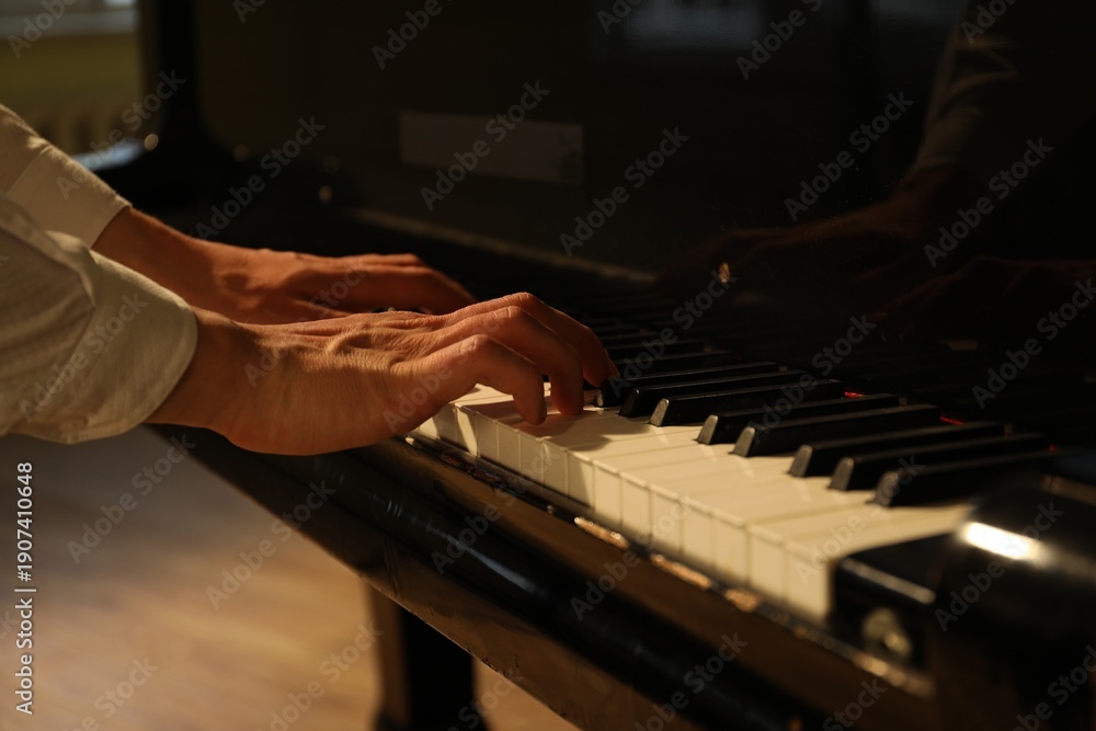 Fototapeta premium Musician playing piano indoors, closeup. Musical instrument