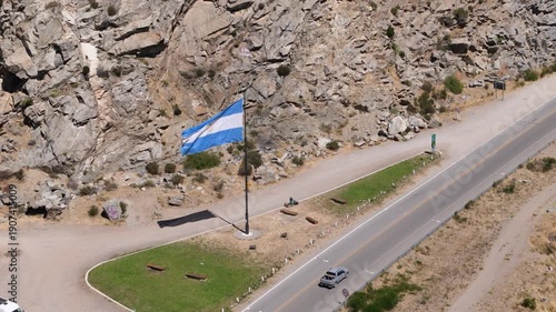 Argentine flag waving proudly over a scenic mountain road in San Martin de los Andes, Neuquen, Patagonia, representing national pride, federalism, and the spirit of the Argentine Republic.