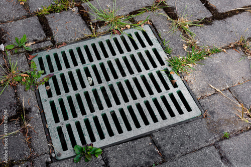 An abstract image of a large square storm drain cover with rectangle paving stones.