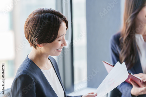 紙資料を持って会議するビジネスパーソン