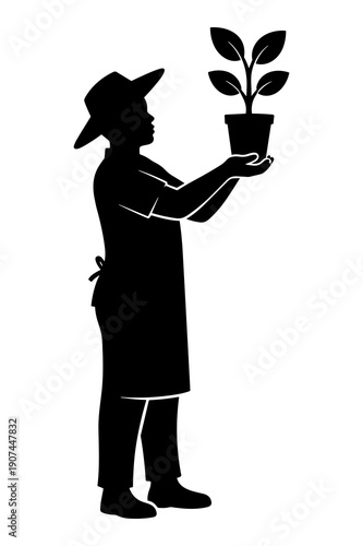 Silhouette of gardener carefully holding up a small potted plant seedling